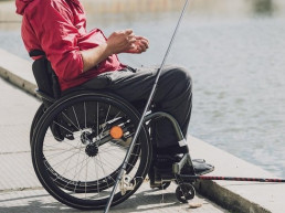 Immagine di un disabile su sedia a rotelle che pesca